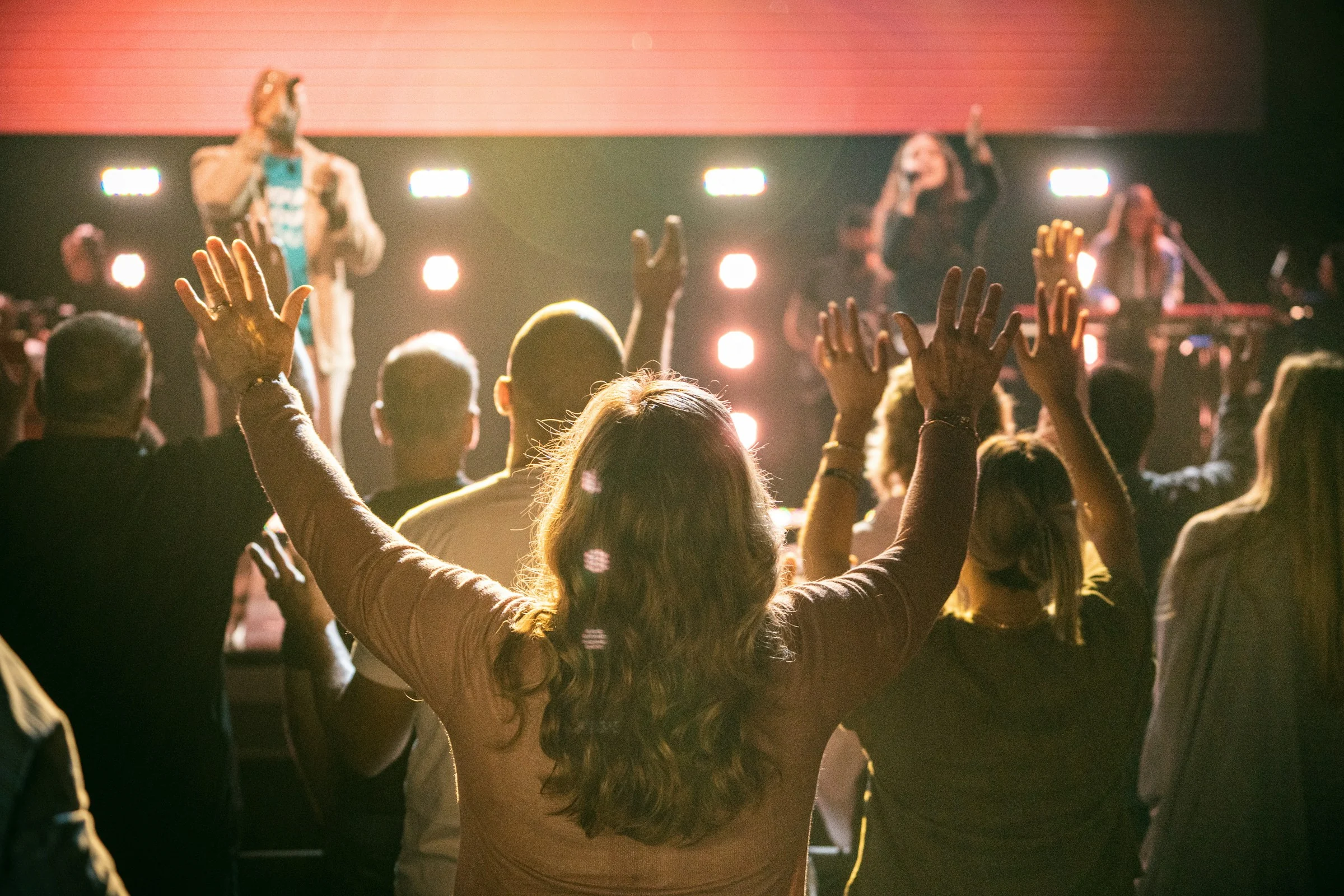 Illustrative worship gathering with people facing a warmly lit stage